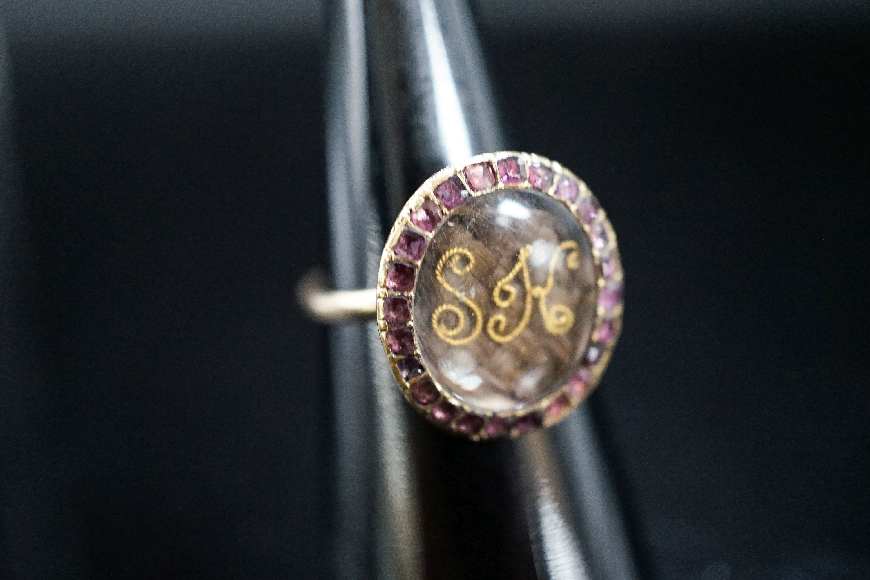 A 19th century yellow metal and gem set mounted glazed mourning ring, with 'S.H.' initialled above plaited hair, size I, gross weight 2.9 grams (adapted).